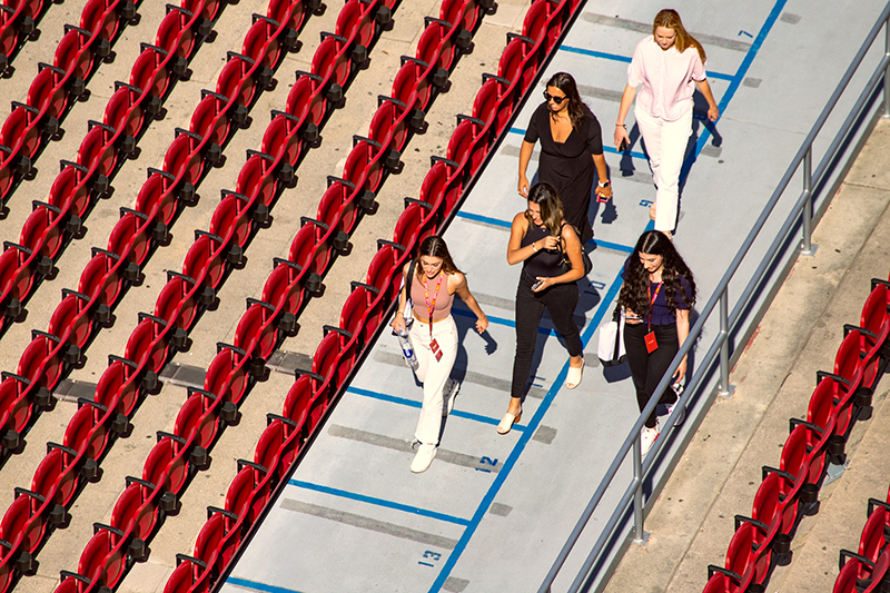 Aerial views of USC prospective law students walking down an aisle flanked by red stadium seats.
