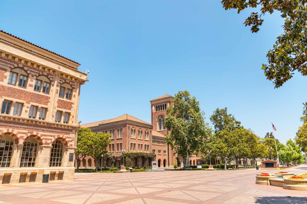 Wide shot of USC University Park Campus Trousdale Boulevard with brick paved walkway and brick architecture and trees.