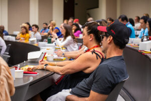 Woman takes notes at Dean Kirschner's lecture to all the Gould Trojan Family Weekend participants