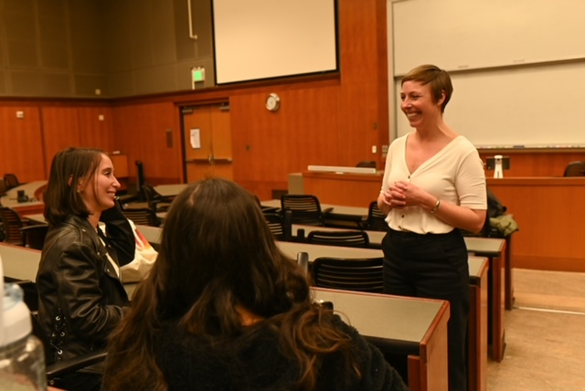 JD alumna, Betsy Popken, stands while speaking to two students in a classroom.