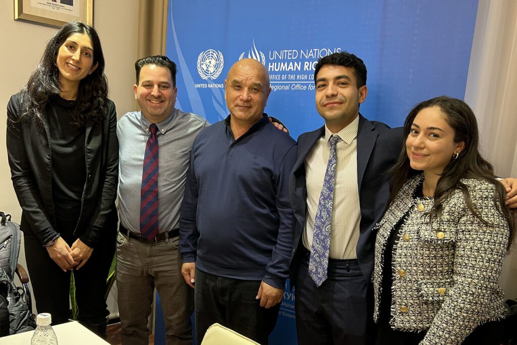 Three JD students of the International Human Rights Clinic, professor Henna Pithia, and head of Ventus, Kamil Ruziev, pose in front of United Nations backdrop.