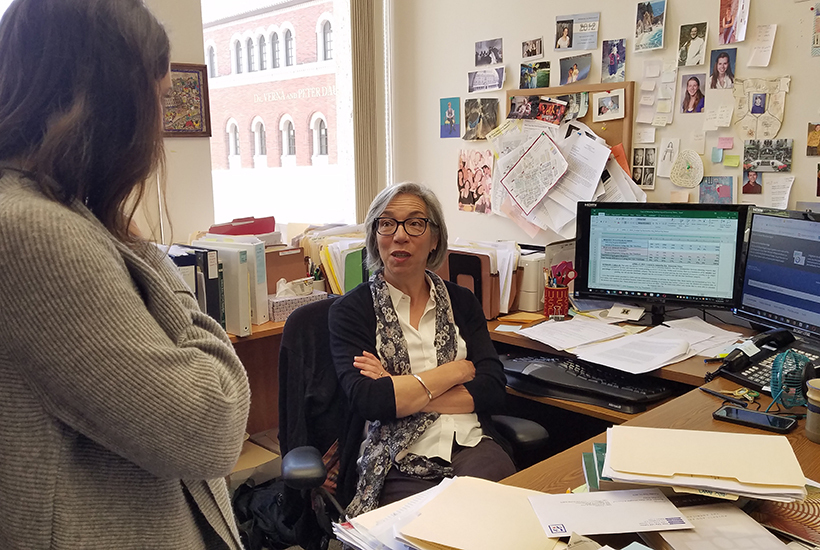 Professor Clare Pastore sitting at her desk speaking with a student in her office.