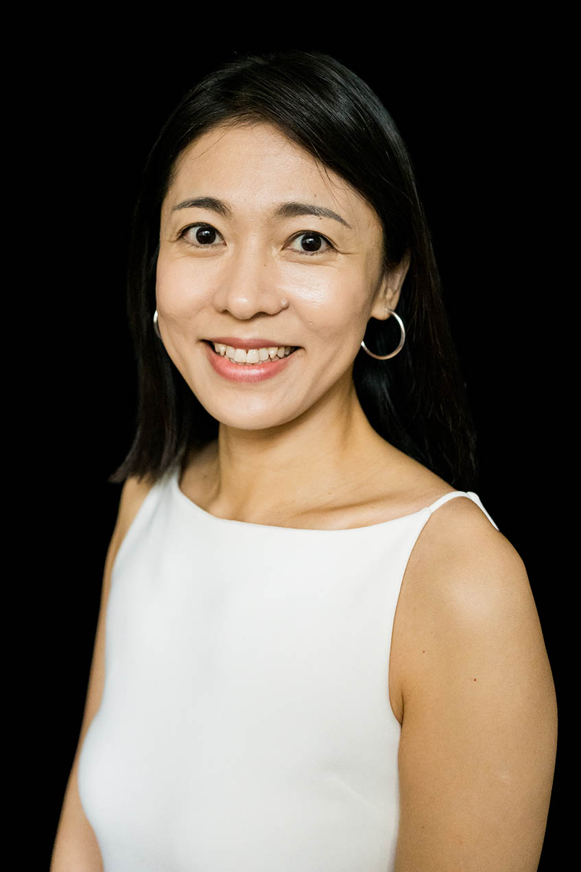 A woman smiles in front of a black background