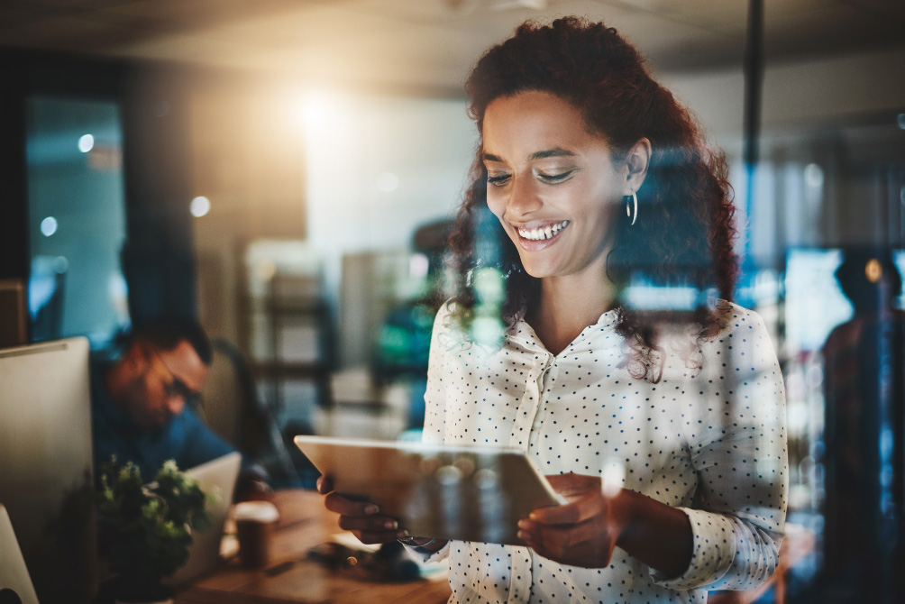 Smiling lawyer looks down at tablet in an office